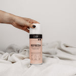 Bag Refresh: Hand greift von links nach dem Produkt auf weißer Decke vor neutralem Hintergrund.
