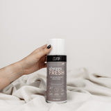 Im Bild ist das Produkt 'Always Fresh' zu sehen, das auf einer weißen Decke vor einem neutralen Hintergrund platziert ist. Eine Hand, von rechts kommend, greift nach dem Produkt. 'Always Fresh' ist ein Produkt zur Geruchsbekämpfung und Bakterienprävention für Schuhe, effektiv und vielseitig für alle Schuharten. Die Szene betont die Hand, die nach diesem Produkt greift, um seine Anwendung oder seine Wirksamkeit zu veranschaulichen.