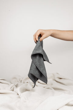 Magic Towel: Von einer Hand gehalten, präsentiert auf neutralem Hintergrund mit einer weißen Decke. Ein vielseitiges und sanftes Reinigungstuch, hervorragend für empfindliche Oberflächen und eine effektive Schmutz- und Feuchtigkeitsaufnahme.