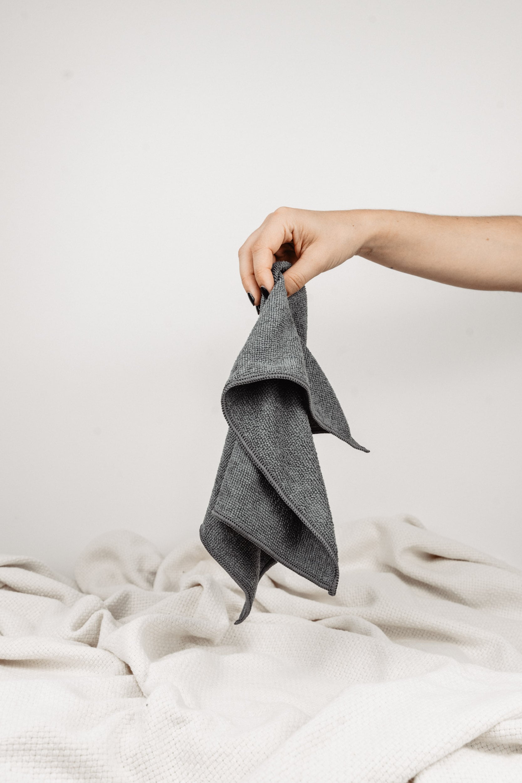 Magic Towel: Von einer Hand gehalten, präsentiert auf neutralem Hintergrund mit einer weißen Decke. Ein vielseitiges und sanftes Reinigungstuch, hervorragend für empfindliche Oberflächen und eine effektive Schmutz- und Feuchtigkeitsaufnahme.