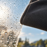 Dunkelgraues LUFIP Ultra Towel nimmt Wasser von einer Fensterscheibe auf und unterstützt streifenfreies Trocknen.