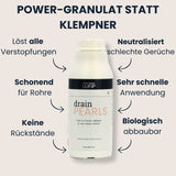 Drain Pearls Flasche in der Bildmitte, Pfeile zeigen Vorteile: löst alle Verstopfungen, schonend für Rohre, keine Rückstände, neutralisiert Gerüche, sehr schnelle Anwendung, biologisch abbaubar; Überschrift „Granulat statt Klempner“.