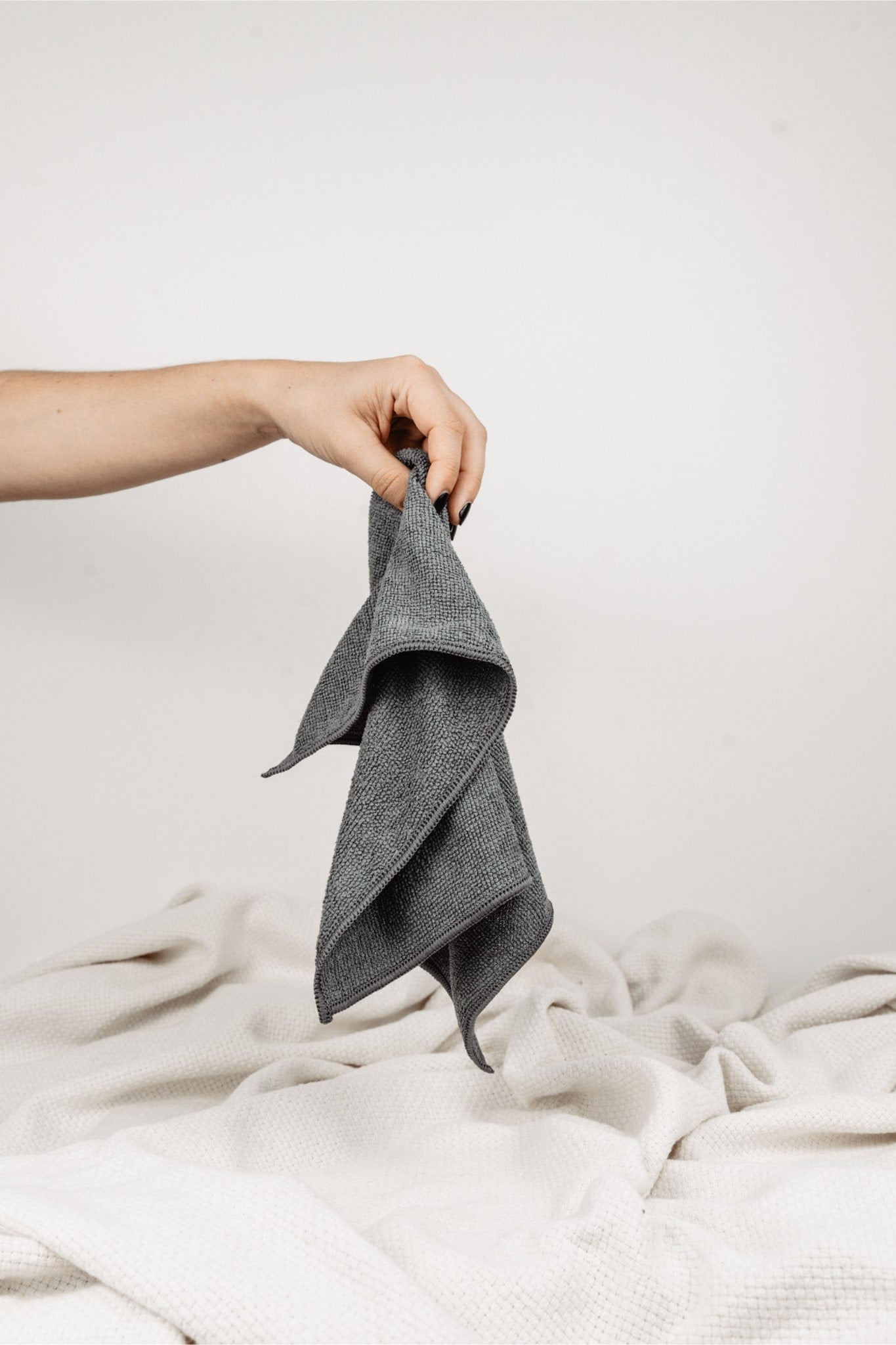 Magic Towel: Von einer Hand gehalten, präsentiert auf neutralem Hintergrund mit einer weißen Decke. Ein vielseitiges und sanftes Reinigungstuch, hervorragend für empfindliche Oberflächen und eine effektive Schmutz- und Feuchtigkeitsaufnahme.