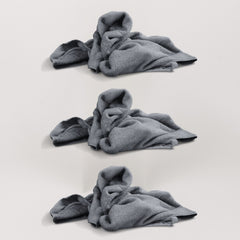 Drei graue, weiche Mikrofasertücher (Magic Towel) liegen übereinander in leicht zerknüllter Form auf einer hellen Oberfläche, dargestellt als Set.